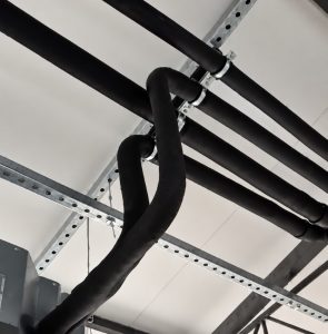 Instalação de climatização com tubulação isolada fixada em suportes modulares tipo trapézio